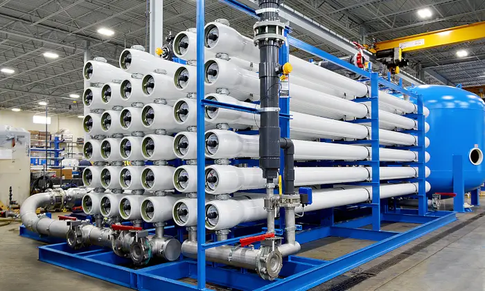 Industrial water filtration system with white filters, blue frame, pipes, and tank in a factory for water treatment by Super quality.